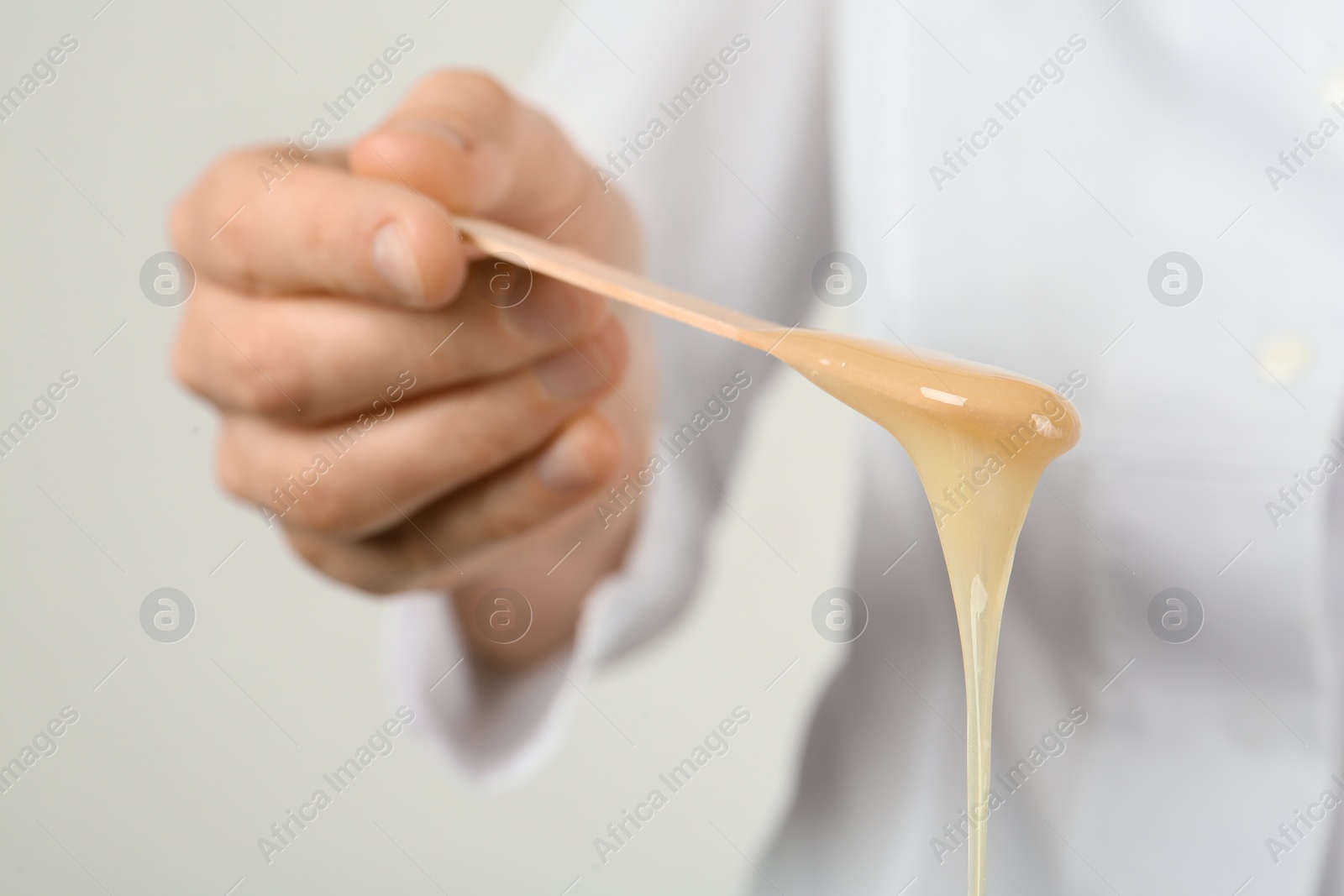 Woman holding spatula with hot depilatory wax, closeup Photo of Woman holding spatula with hot depilatory wax, closeup