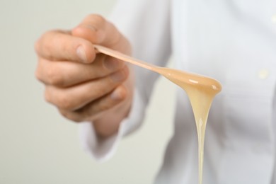Woman holding spatula with hot depilatory wax, closeup Photo of Woman holding spatula with hot depilatory wax, closeup