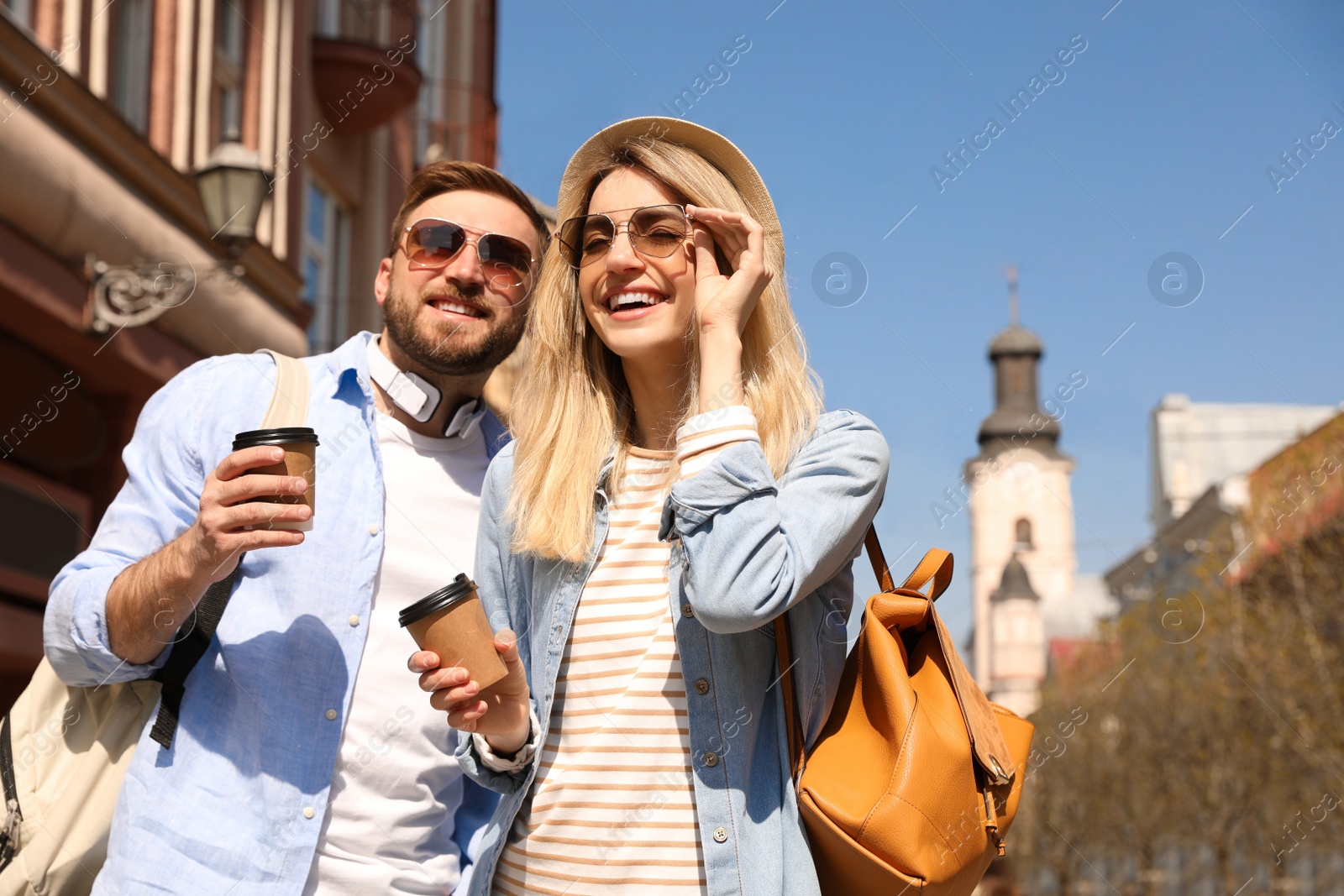 Happy couple with coffee on city street in morning Photo of Happy couple with coffee on city street in morning