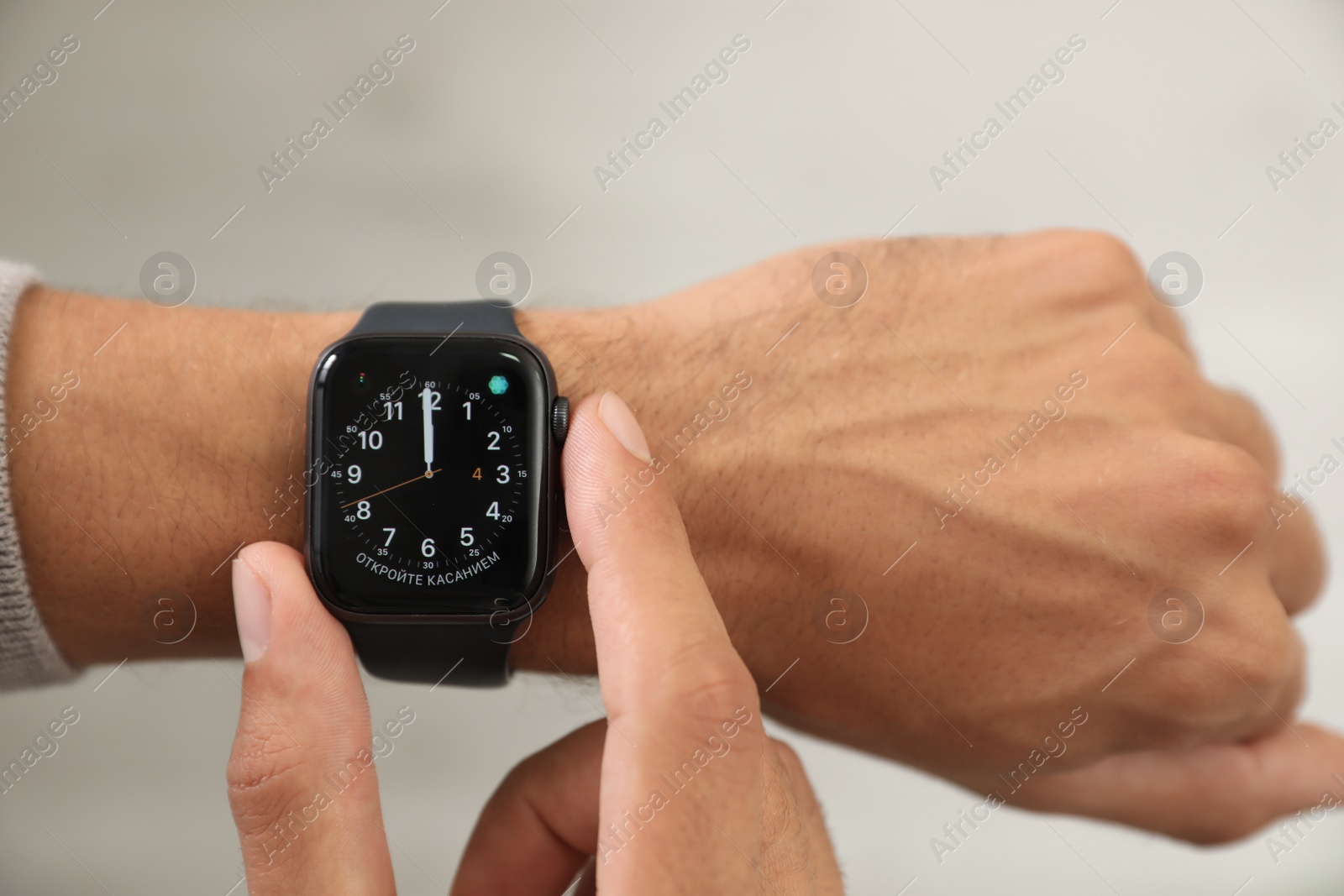 MYKOLAIV, UKRAINE - OCTOBER 04, 2019: Man using Apple Watch to check time on light background, closeup Image of MYKOLAIV, UKRAINE - OCTOBER 04, 2019: Man using Apple Watch to check time on light background, closeup