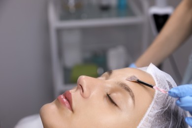 Cosmetologist applying chemical peel product on client's face in salon Photo of Cosmetologist applying chemical peel product on client's face in salon