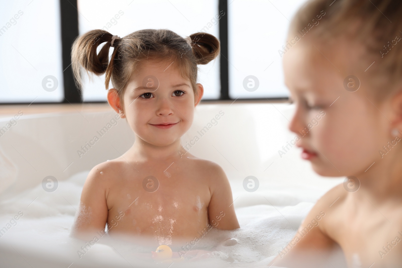 Cute little sisters taking bubble bath together Photo of Cute little sisters taking bubble bath together