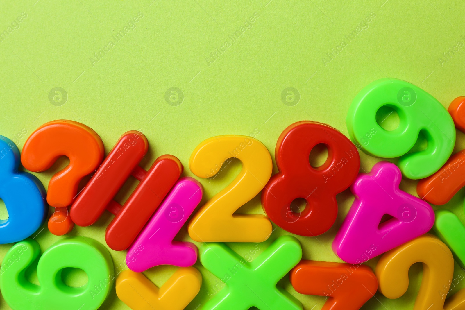 Colorful magnetic numbers on light green background, flat lay Photo of Colorful magnetic numbers on light green background, flat lay