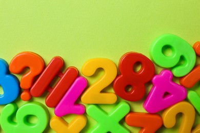 Colorful magnetic numbers on light green background, flat lay Photo of Colorful magnetic numbers on light green background, flat lay