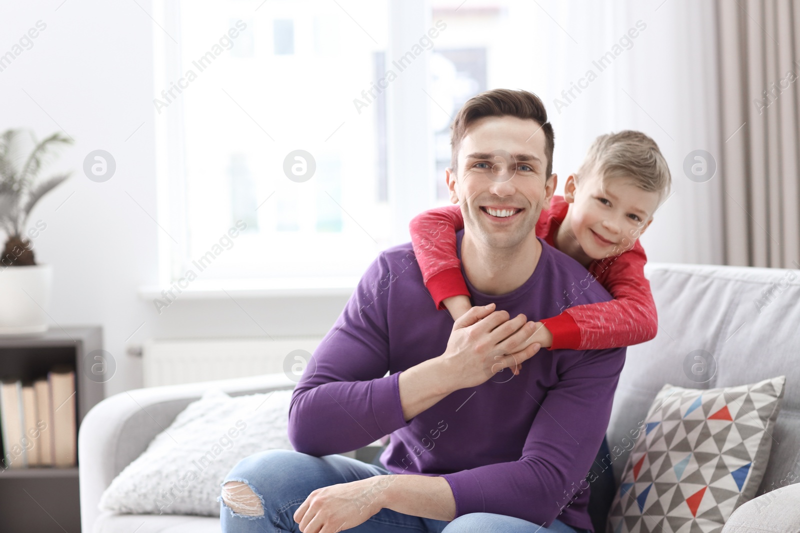 Dad and his son sitting on sofa at home Photo of Dad and his son sitting on sofa at home