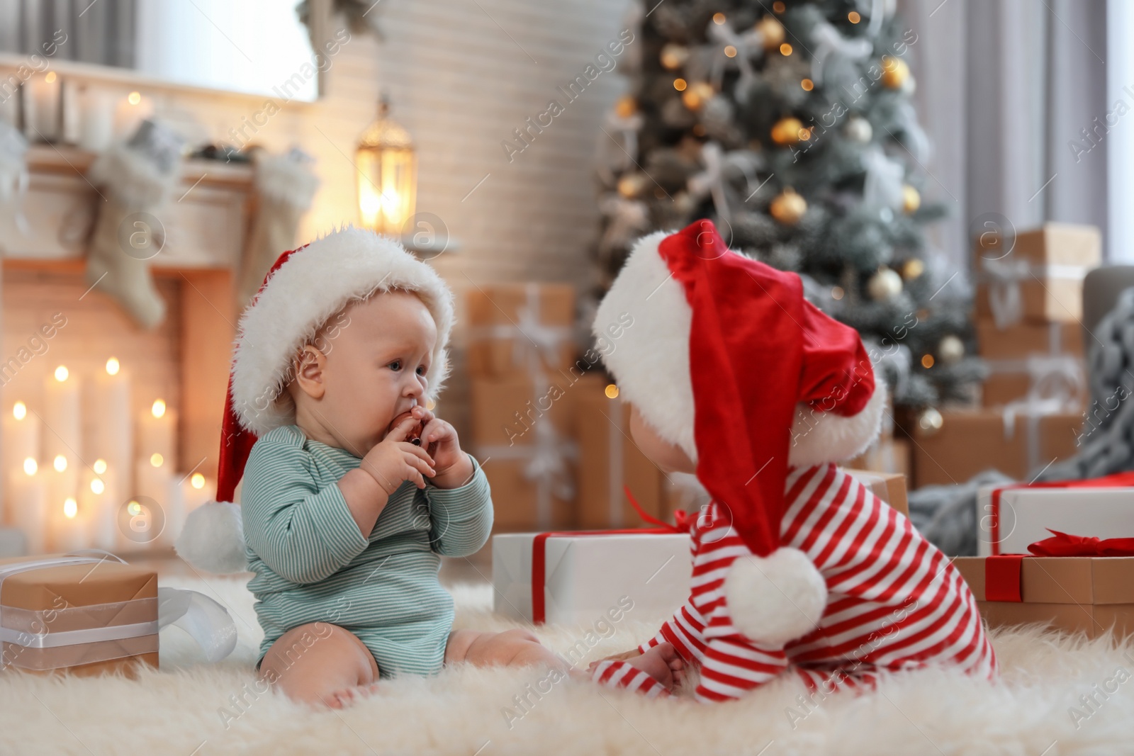 Cute children in Santa hats on floor in room with Christmas tree Image of Cute children in Santa hats on floor in room with Christmas tree