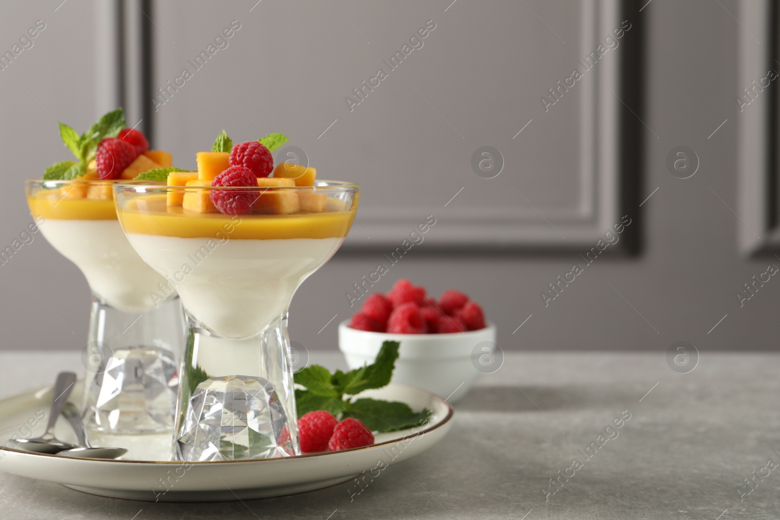 Delicious panna cotta with mango and raspberries on grey table. Space for text Photo of Delicious panna cotta with mango and raspberries on grey table. Space for text
