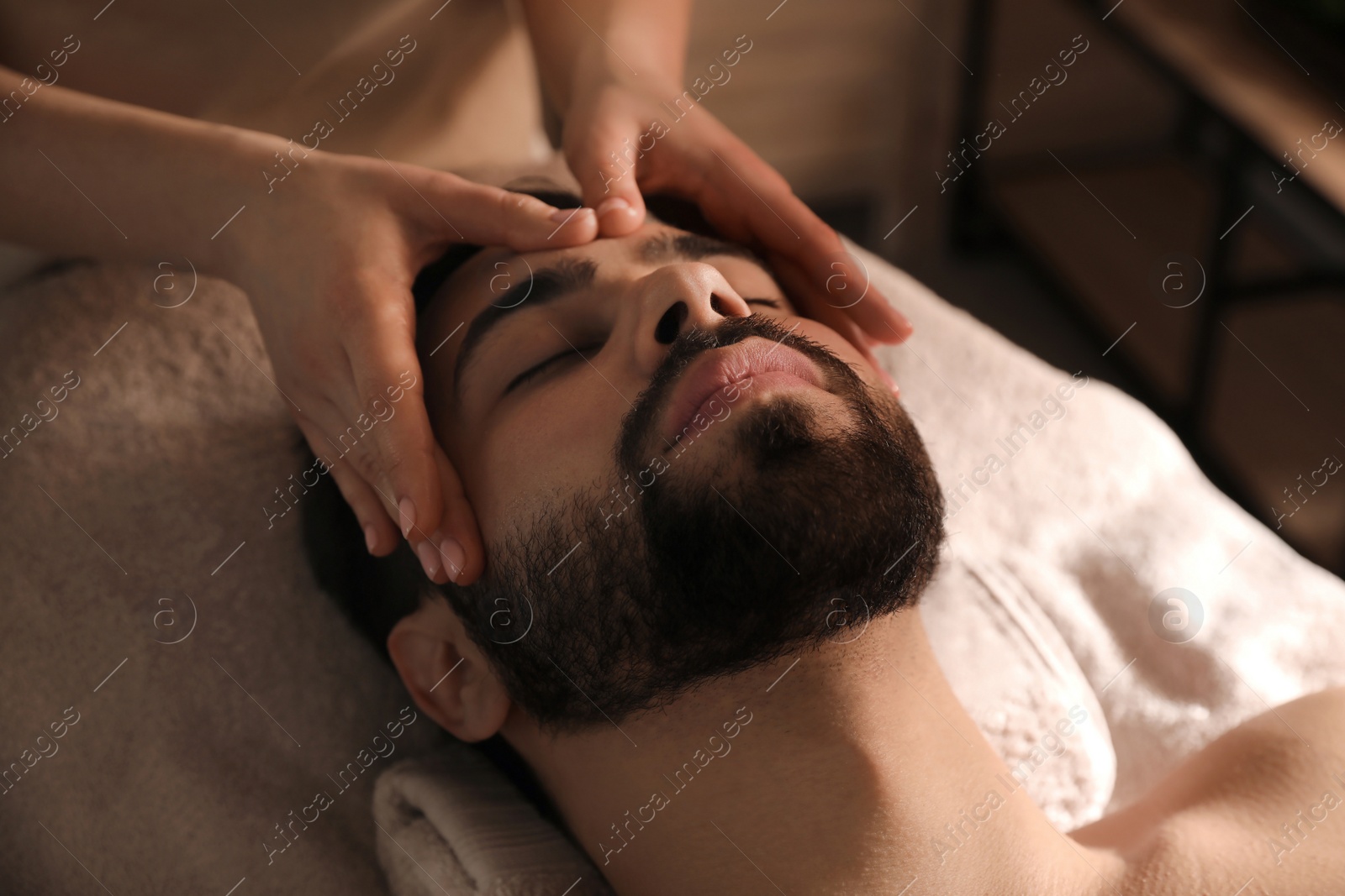 Young man receiving facial massage in beauty salon Photo of Young man receiving facial massage in beauty salon