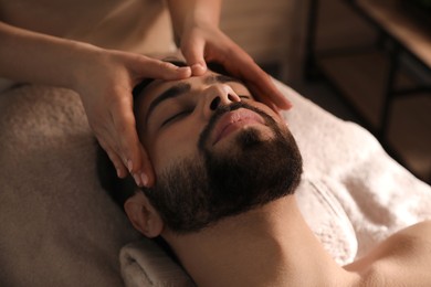 Young man receiving facial massage in beauty salon Photo of Young man receiving facial massage in beauty salon