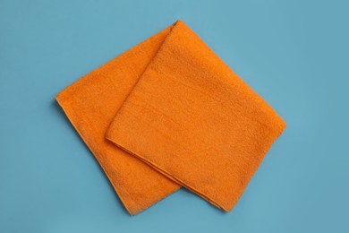 Folded orange beach towel on light blue background, top view Photo of Folded orange beach towel on light blue background, top view