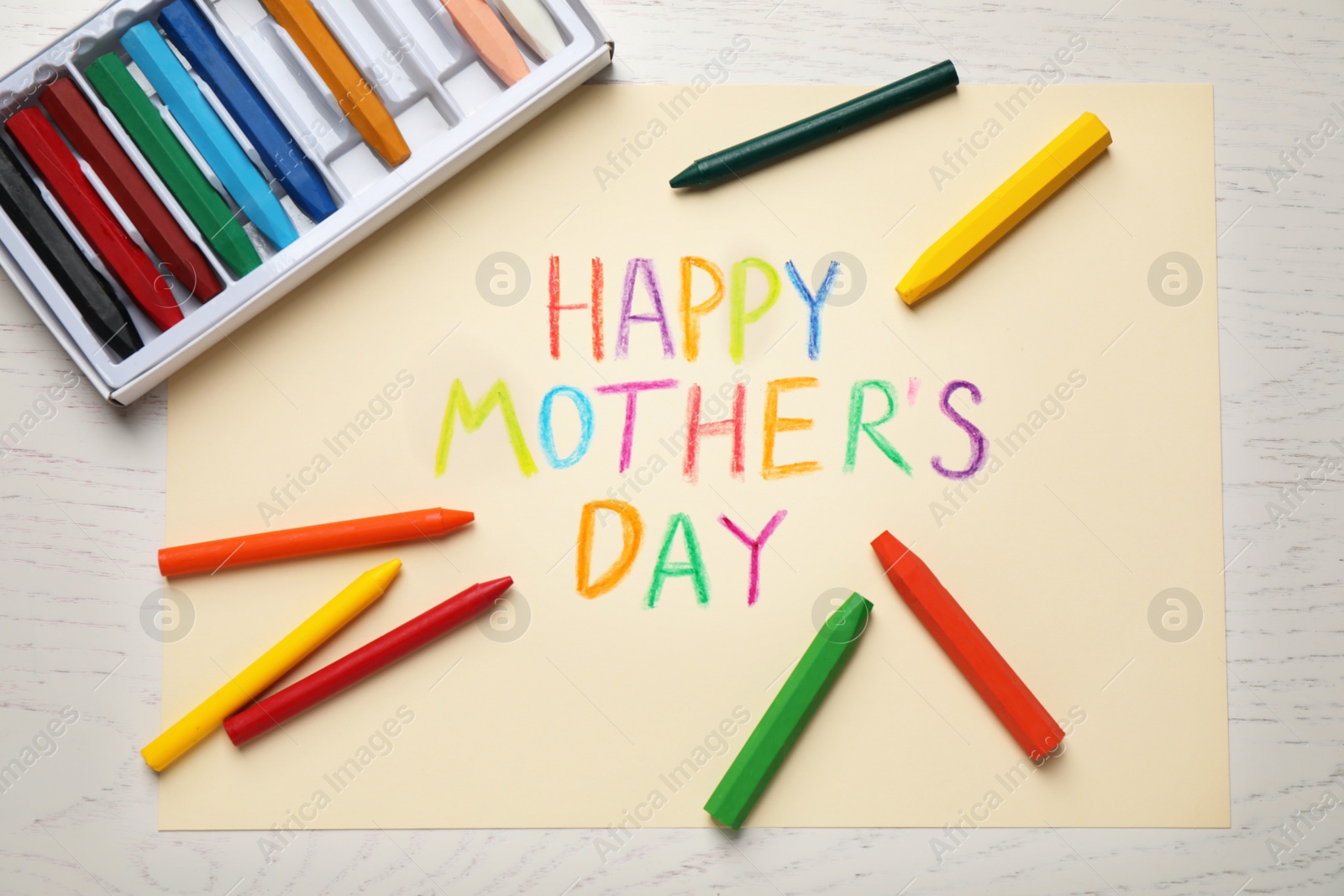 Greeting card for Mother's day and crayons on white wooden background, flat lay Photo of Greeting card for Mother's day and crayons on white wooden background, flat lay
