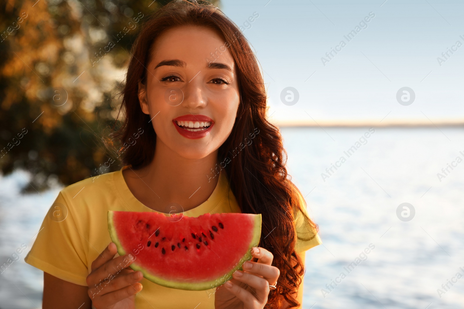 Beautiful young woman with watermelon near river at sunset Photo of Beautiful young woman with watermelon near river at sunset