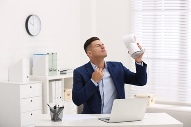 Man enjoying air flow from fan at workplace Photo of Man enjoying air flow from fan at workplace