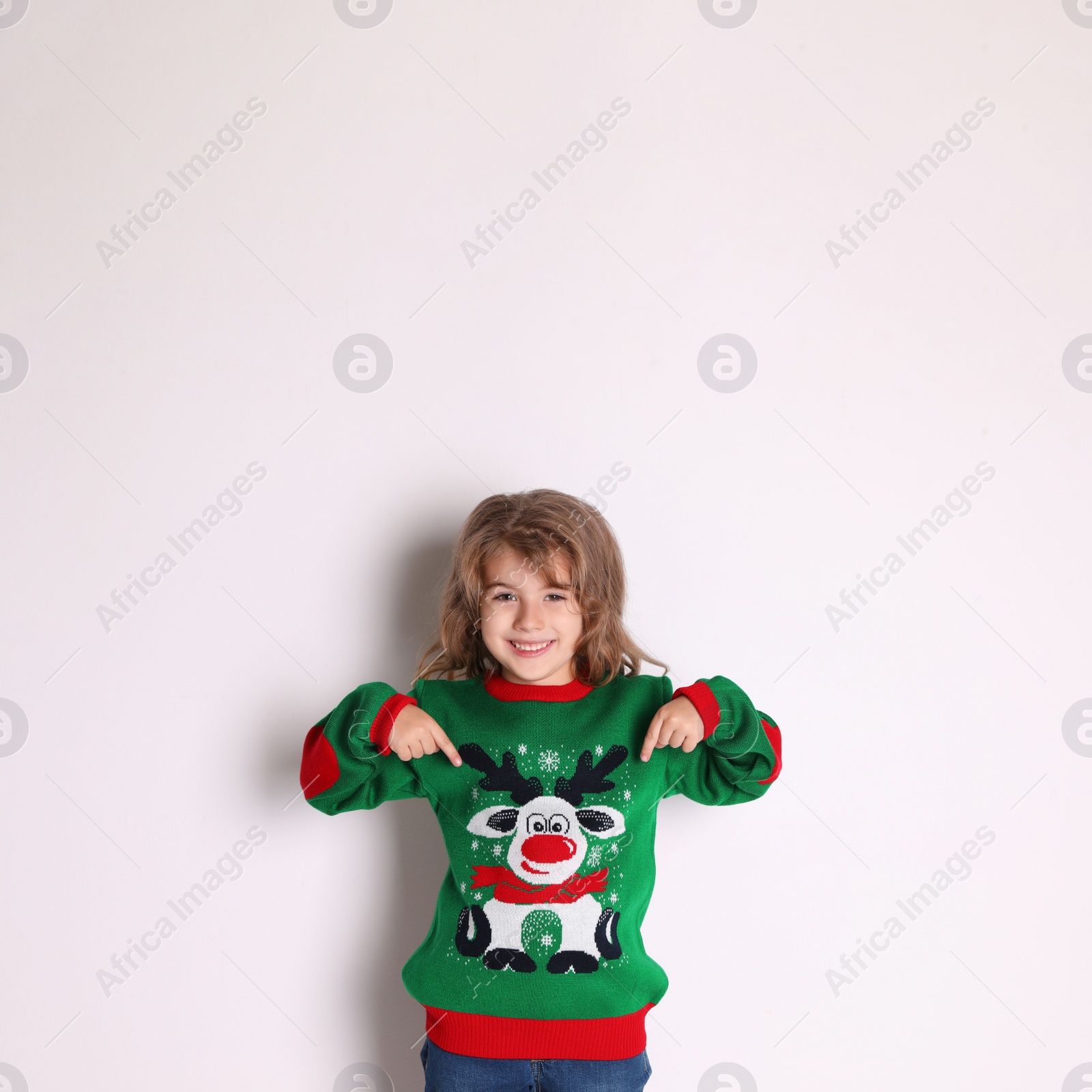 Cute little girl pointing at her green Christmas sweater against white background Photo of Cute little girl pointing at her green Christmas sweater against white background