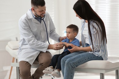 Mother and son visiting pediatrician in hospital. Doctor examining little boy Photo of Mother and son visiting pediatrician in hospital. Doctor examining little boy