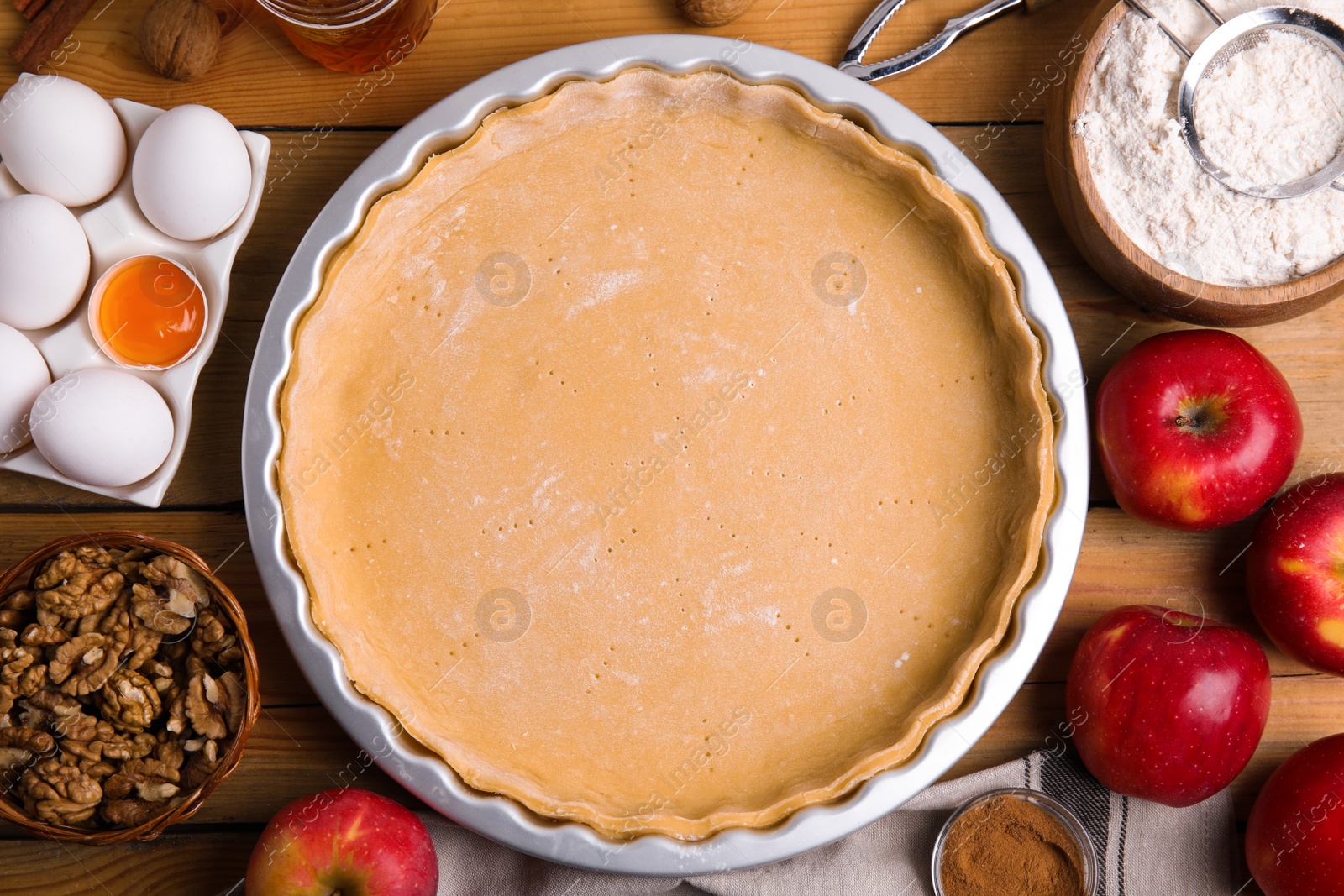 Raw dough and ingredients for traditional English apple pie on wooden table, flat lay Photo of Raw dough and ingredients for traditional English apple pie on wooden table, flat lay