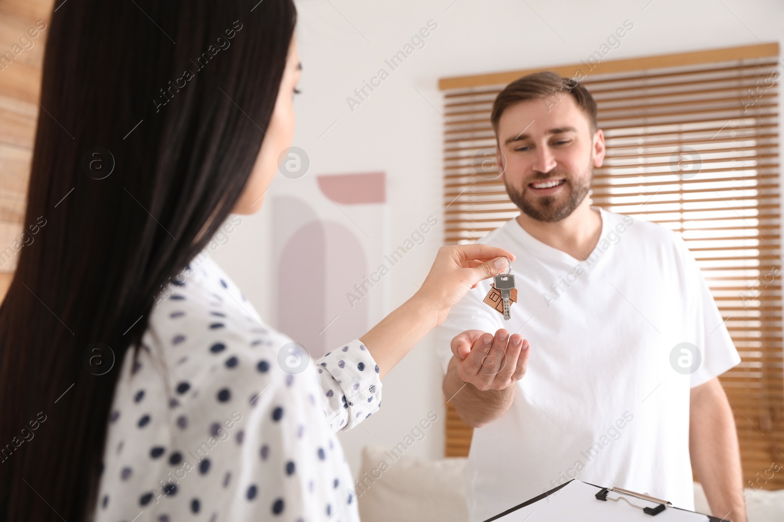 Real estate agent giving key to happy young man in new house, focus on hands Photo of Real estate agent giving key to happy young man in new house, focus on hands