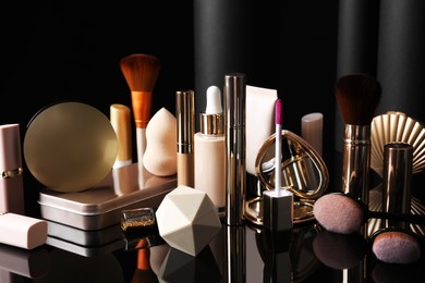 Composition with makeup products on table against black background Photo of Composition with makeup products on table against black background