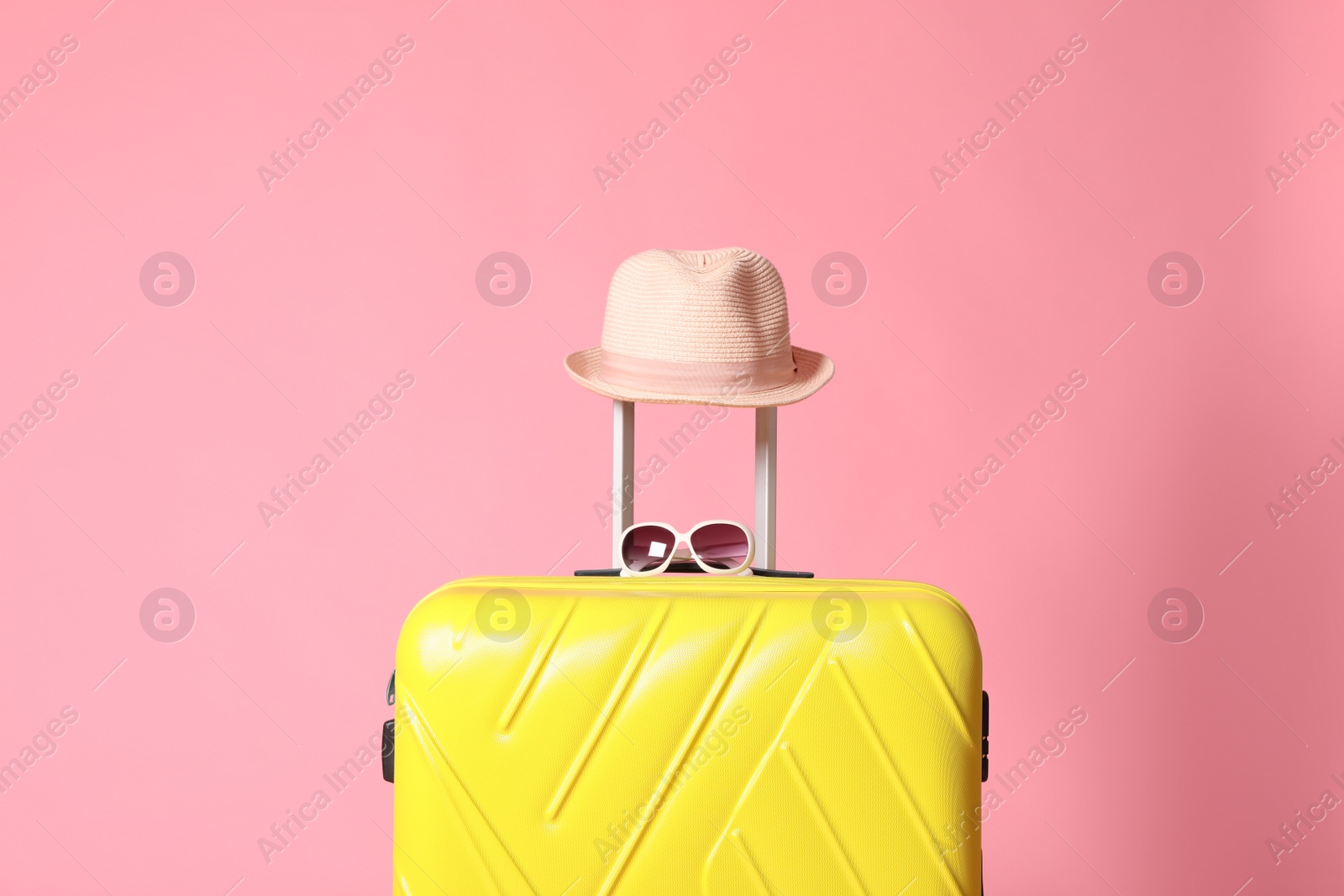 Yellow suitcase with sunglasses and hat on pink background Photo of Yellow suitcase with sunglasses and hat on pink background