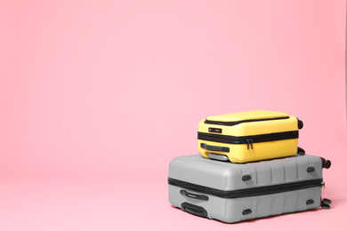 Photo of Stylish yellow and grey suitcases on pink background. Space for text