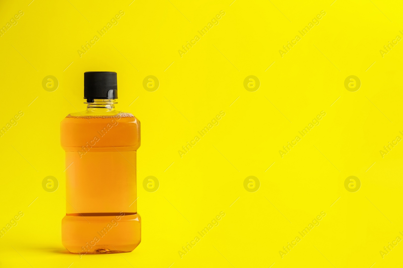 Mouthwash on yellow background, space for text Photo of Mouthwash on yellow background, space for text