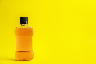 Mouthwash on yellow background, space for text Photo of Mouthwash on yellow background, space for text