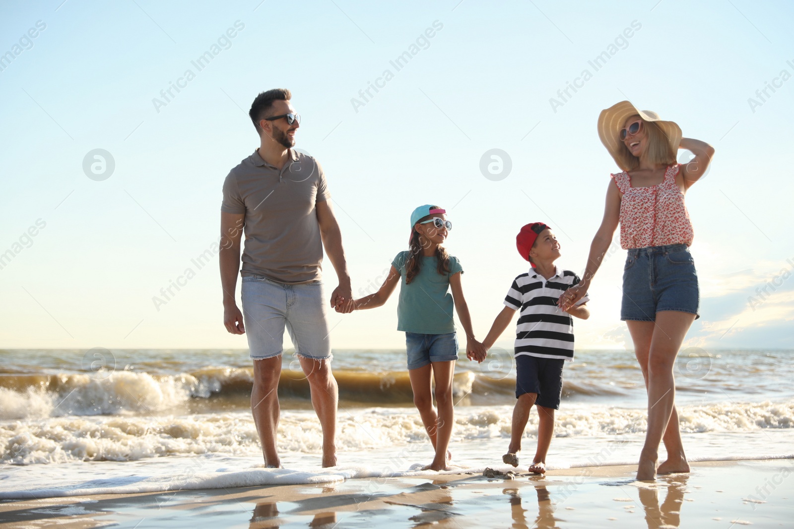 Photo of Happy family walking on sandy beach near sea