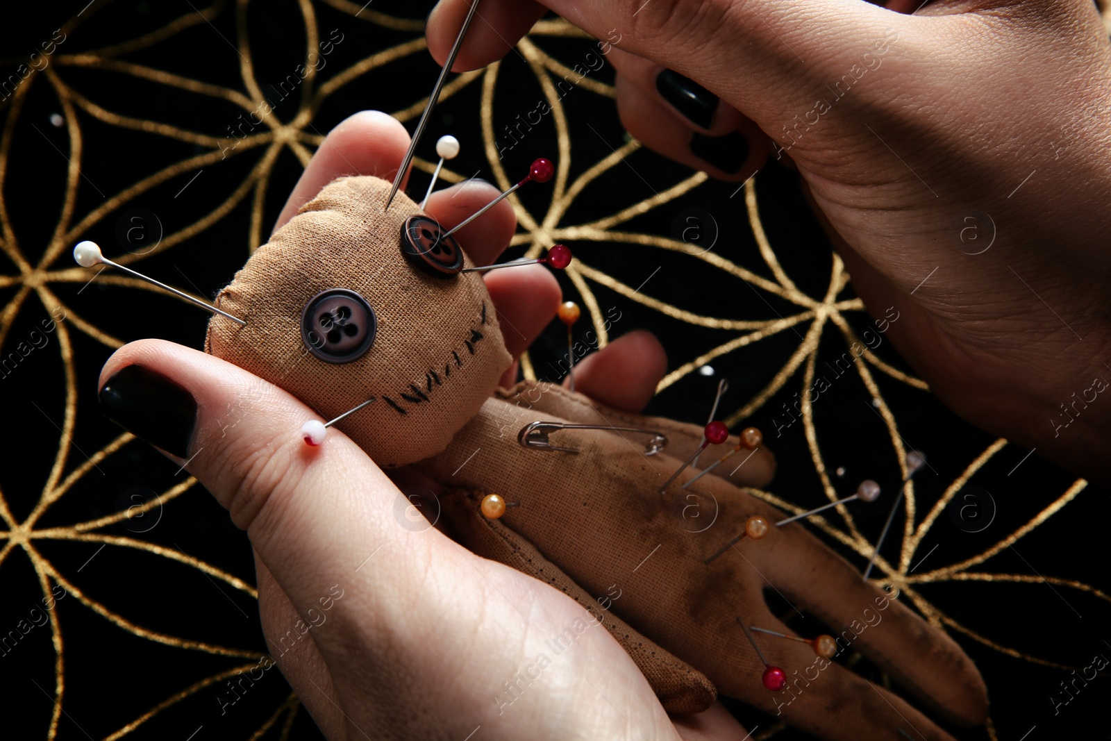 Woman stabbing voodoo doll with needle at table, closeup. Curse ceremony Photo of Woman stabbing voodoo doll with needle at table, closeup. Curse ceremony