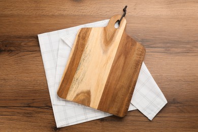 Kitchen towel and cutting board on wooden table, top view Photo of Kitchen towel and cutting board on wooden table, top view