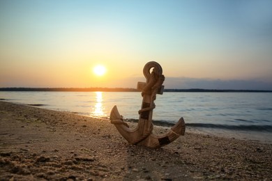 Wooden anchor on shore near river at sunset Photo of Wooden anchor on shore near river at sunset