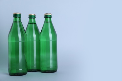 Glass bottles with water on white background, space for text Photo of Glass bottles with water on white background, space for text