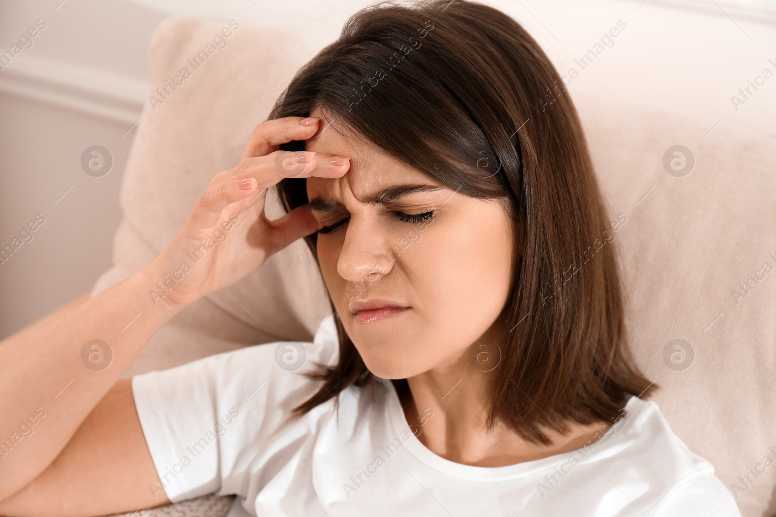 Young woman suffering from migraine on sofa at home Photo of Young woman suffering from migraine on sofa at home