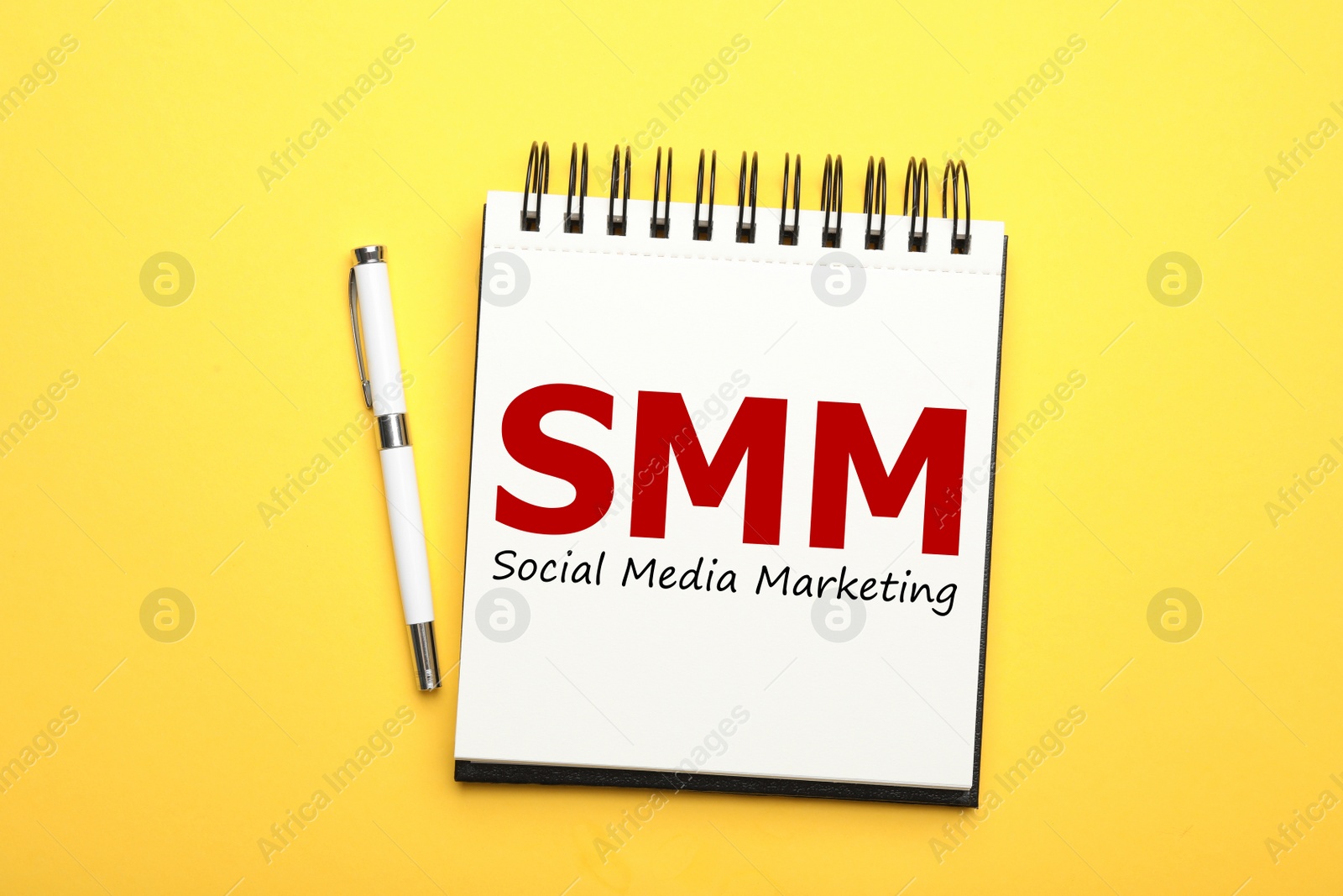 Notebook with text SMM (Social media marketing) and pen on yellow background, flat lay Image of Notebook with text SMM (Social media marketing) and pen on yellow background, flat lay