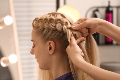 Professional stylist braiding client's hair in salon Photo of Professional stylist braiding client's hair in salon