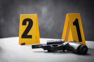 Handgun and crime scene markers on light grey marble table, closeup Photo of Handgun and crime scene markers on light grey marble table, closeup