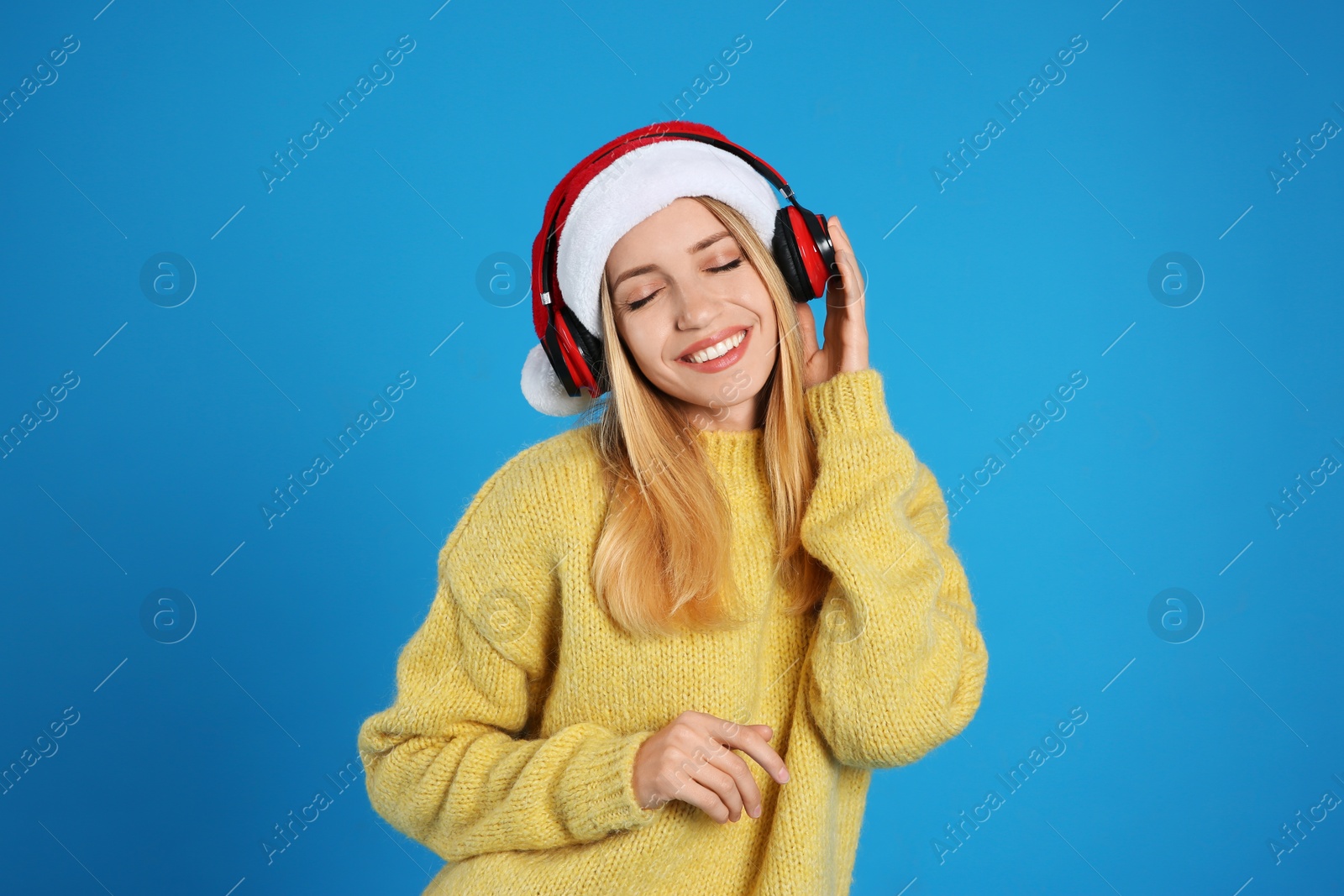 Happy woman with headphones on blue background. Christmas music Photo of Happy woman with headphones on blue background. Christmas music