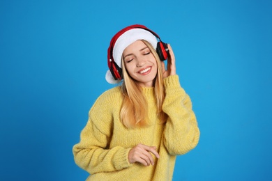 Happy woman with headphones on blue background. Christmas music Photo of Happy woman with headphones on blue background. Christmas music