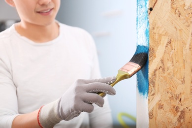 Male decorator painting wall with brush indoors Photo of Male decorator painting wall with brush indoors