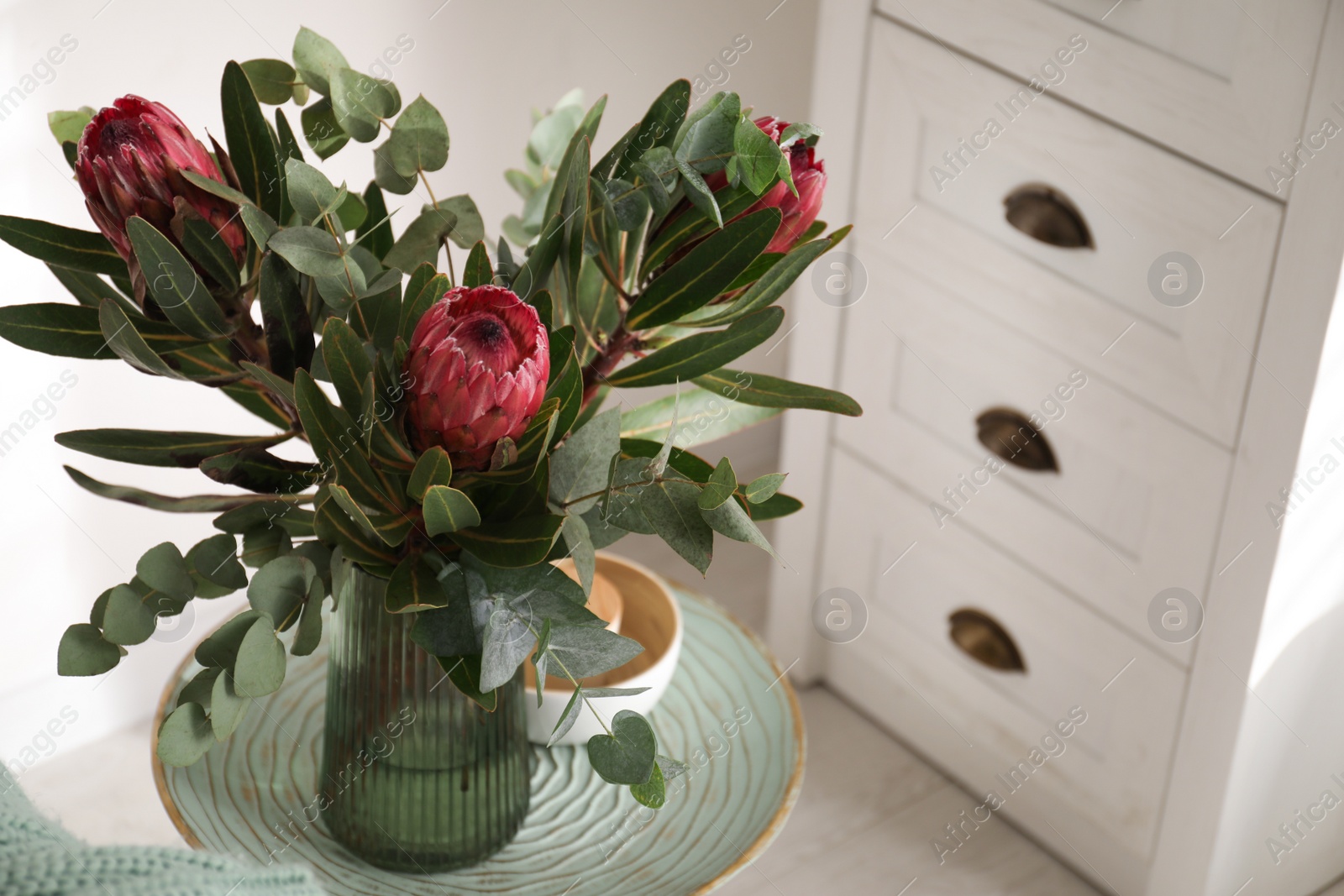 Vase with bouquet of beautiful Protea flowers on table in room Photo of Vase with bouquet of beautiful Protea flowers on table in room