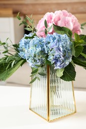 Beautiful hortensia flowers in vase on white table indoors Photo of Beautiful hortensia flowers in vase on white table indoors