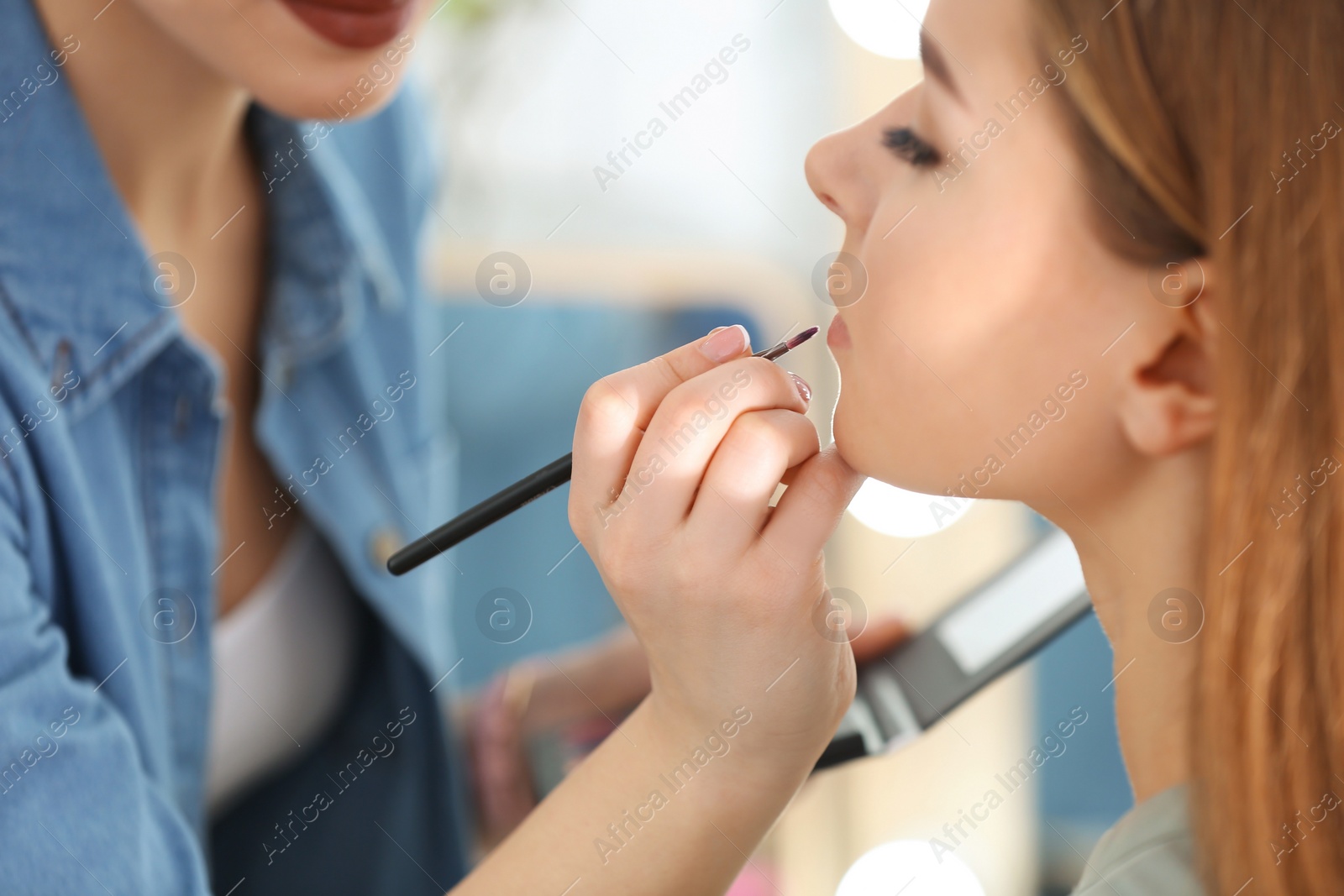 Professional visage artist applying makeup on woman's face in salon, closeup Photo of Professional visage artist applying makeup on woman's face in salon, closeup