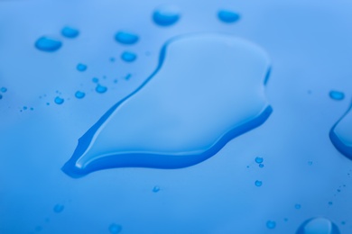 Drops of spilled water on blue background, closeup Photo of Drops of spilled water on blue background, closeup