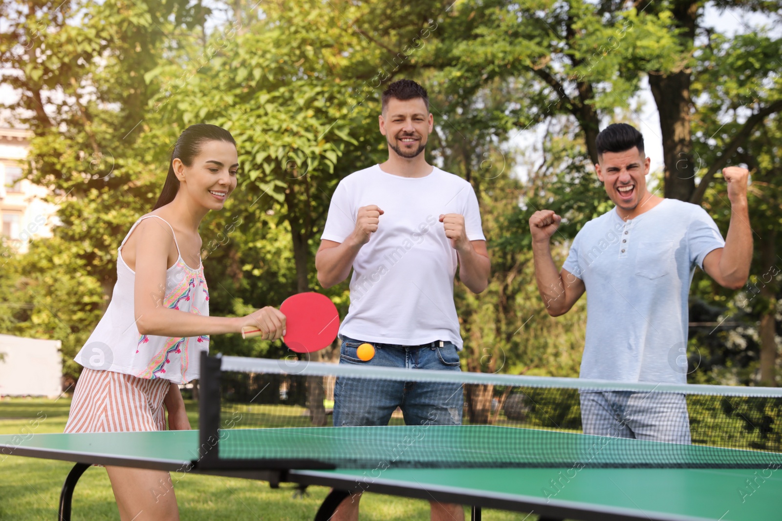 Friends playing ping pong outdoors on summer day Photo of Friends playing ping pong outdoors on summer day