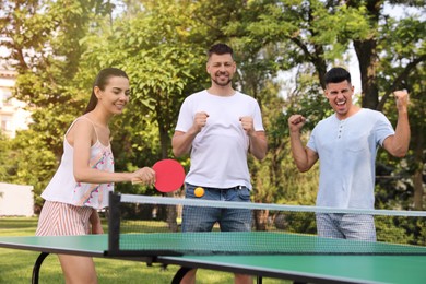 Photo of Friends playing ping pong outdoors on summer day