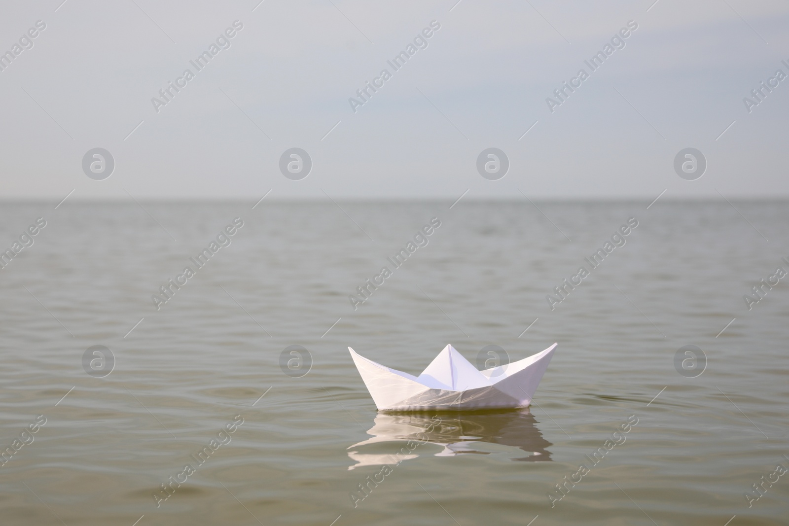 White paper boat on water surface, space for text Photo of White paper boat on water surface, space for text