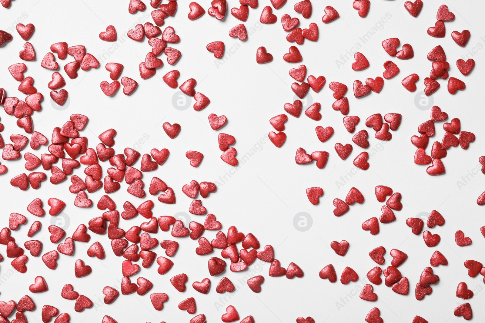Bright heart shaped sprinkles on white background, flat lay Photo of Bright heart shaped sprinkles on white background, flat lay