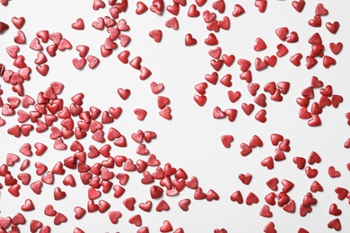 Bright heart shaped sprinkles on white background, flat lay Photo of Bright heart shaped sprinkles on white background, flat lay