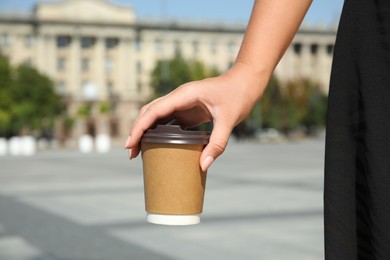 Woman holding takeaway cardboard coffee cup with plastic lid outdoors, closeup Photo of Woman holding takeaway cardboard coffee cup with plastic lid outdoors, closeup