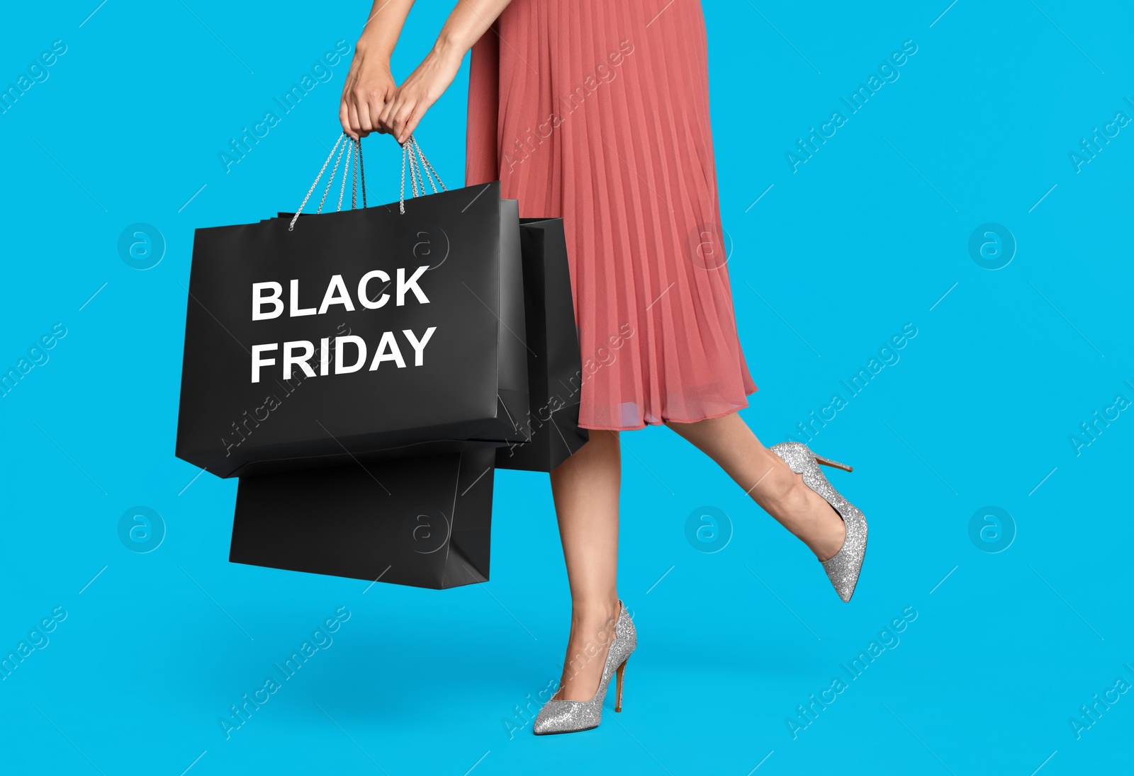 Woman with shopping bags on light blue background, closeup. Black Friday Photo of Woman with shopping bags on light blue background, closeup. Black Friday