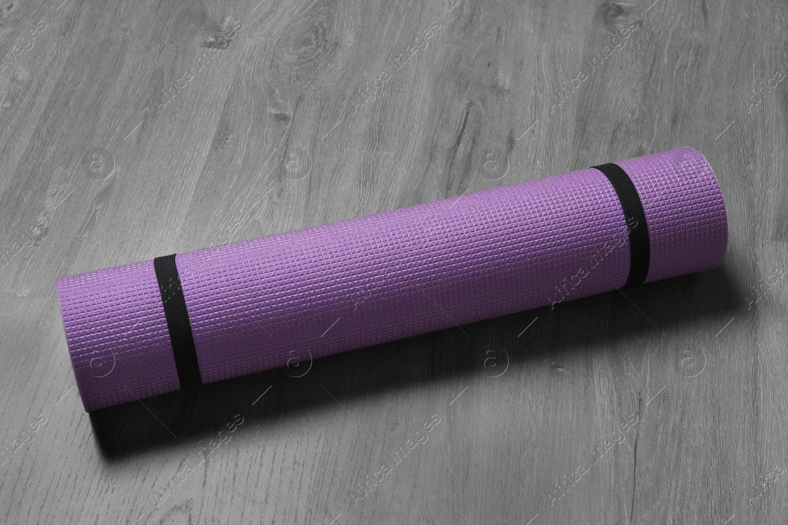 Bright rolled camping mat on grey wooden background Photo of Bright rolled camping mat on grey wooden background